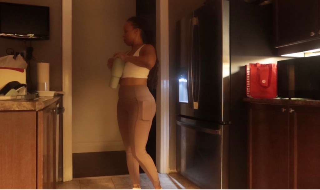 Angel Deen in her kitchen early morning holding a water bottle in athletic wear, holistic wellness morning routine for women over 40